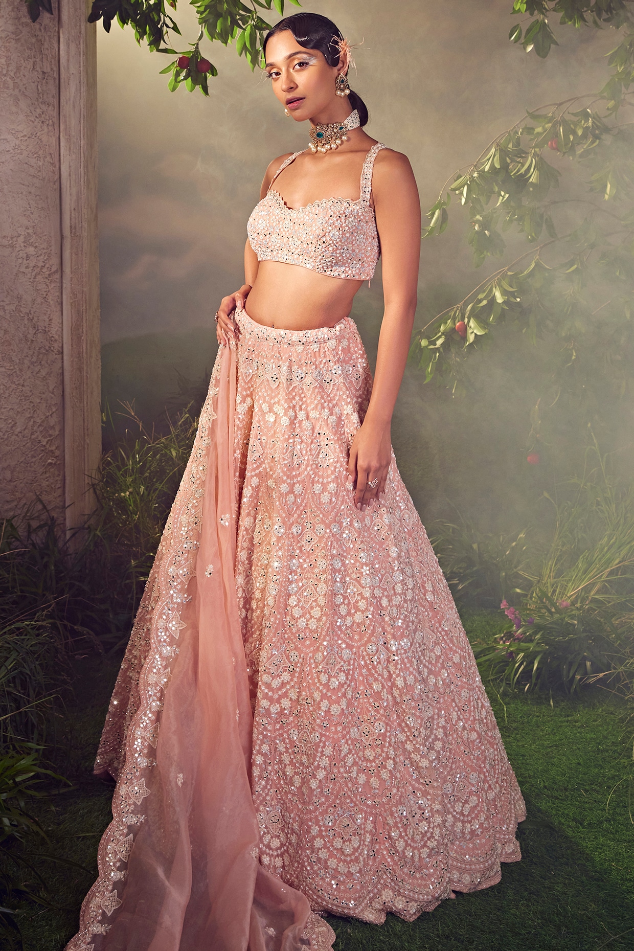 Photo of Bride wearing a pastel pink lehenga with a choker necklace.