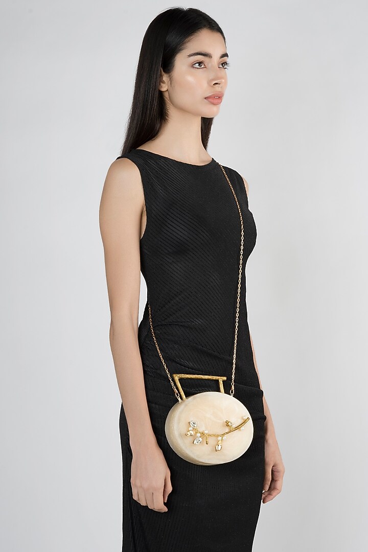 Beige Metal Embellished Oval Clutch by A Clutch Story at Pernia's Pop Up Shop