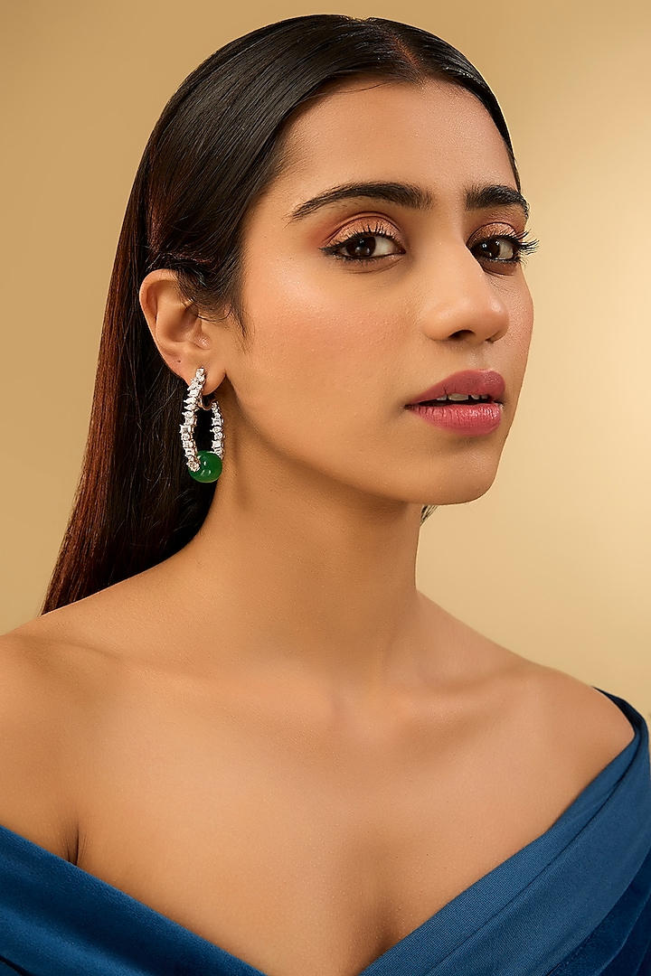 White Gold Finish Eurostar Zircons & Glass-Filled Emerald Stone Hoop Earrings In Sterling Silver by STELLA CREATIONS at Pernia's Pop Up Shop